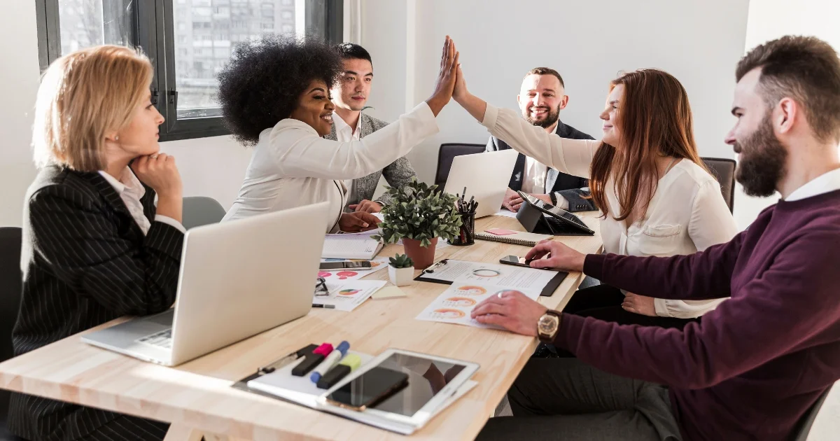 Diverse team in a business meeting celebrating success with a high-five.